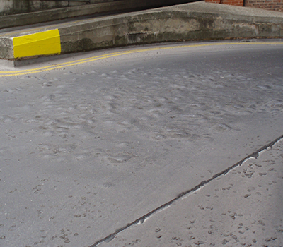 Image of an asphalt car park with blisters